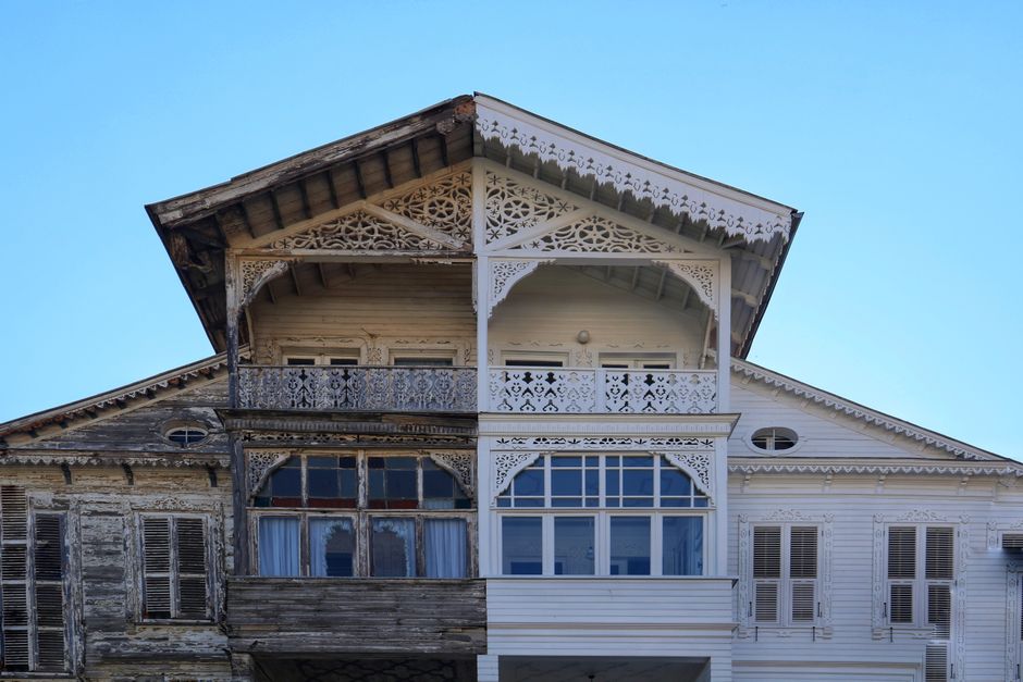 The image shows a view of a bright blue sky with scattered white clouds, seen from inside a property through a partially open roof window. The roof window frame is visible at the top of the image, wit